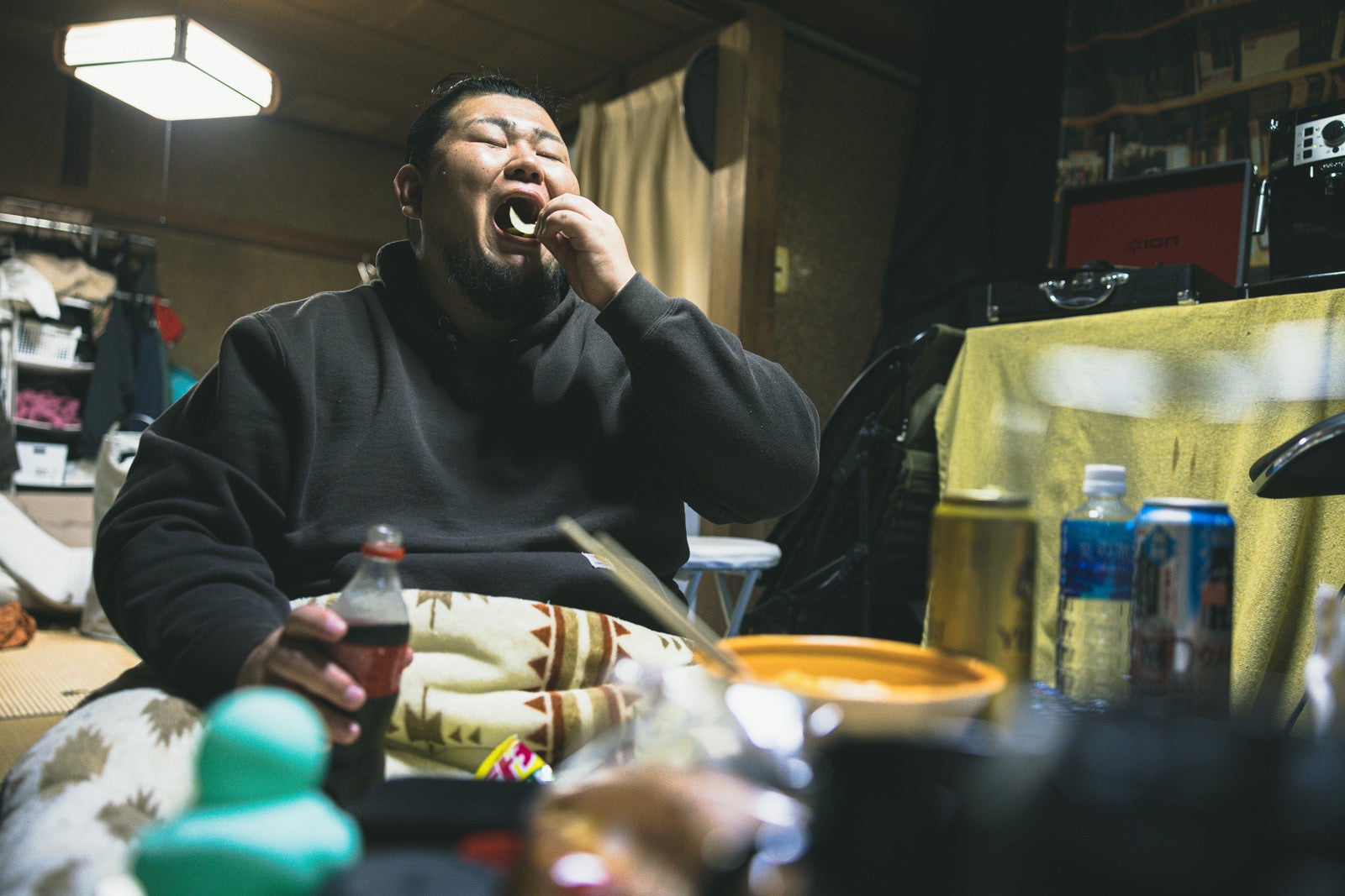 「大きな口でポテトッチップスを頬張る無精髭の男性」の写真［モデル：ノリックス］