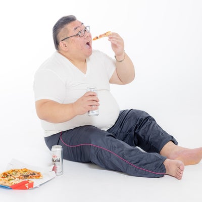 大きな口でピザを食す膨よかな男性の写真