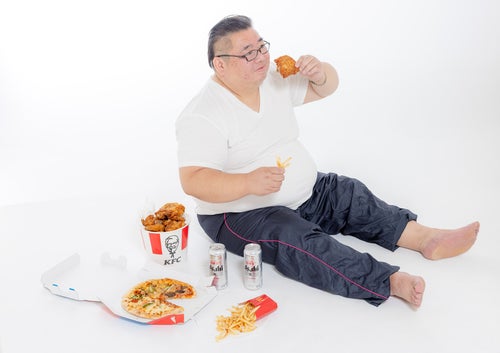 暴飲暴食する肥満男性の写真