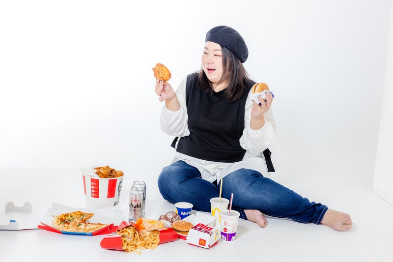 ファーストフードに囲まれて微笑む女性の写真