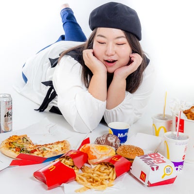 ジャンクフードを前に顎のせポーズの女性の写真