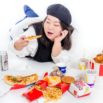 休みの日は頬杖をついてジャンクフードを食す女性の写真