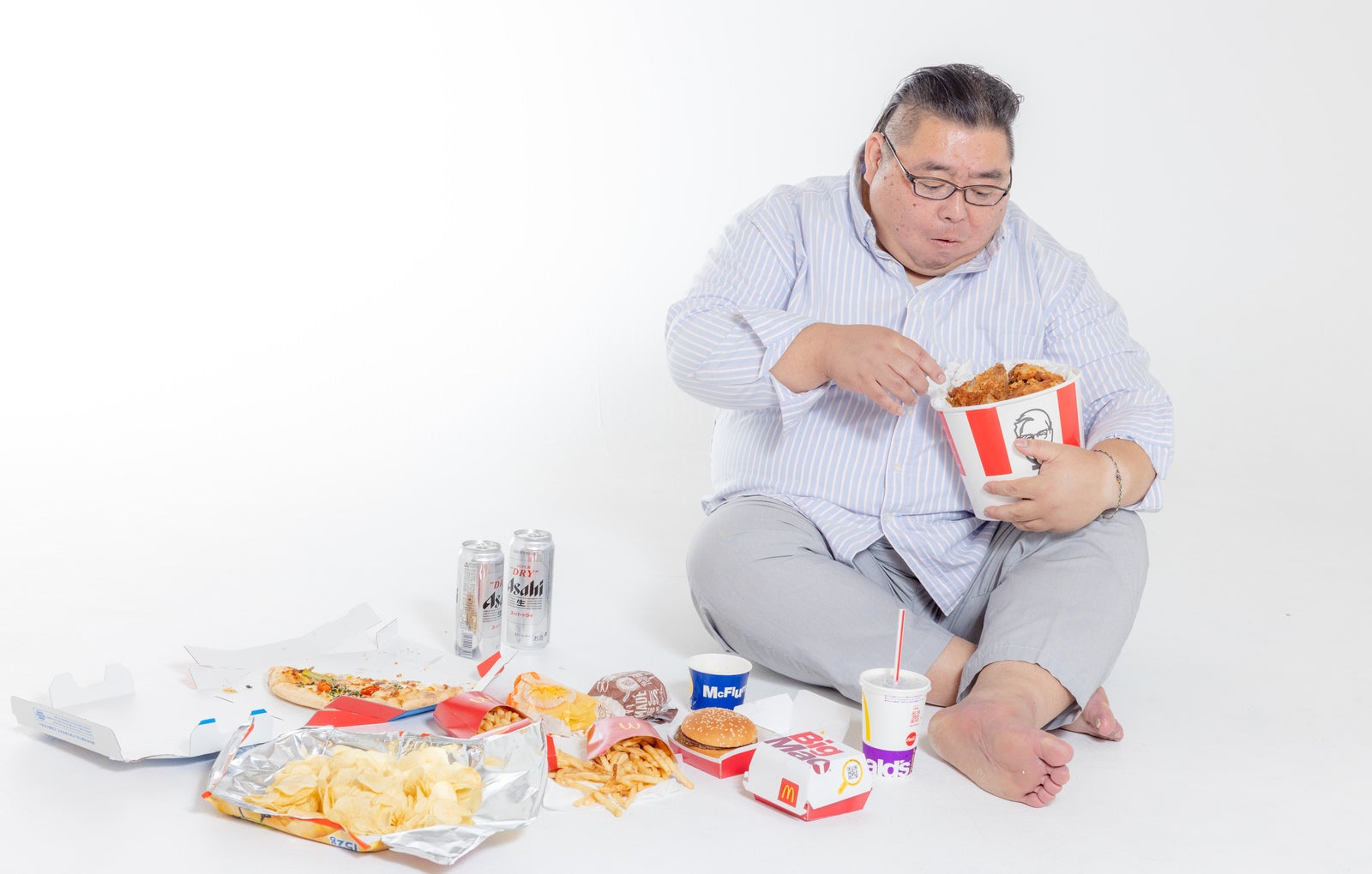「ケンタを食べながら暴飲暴食男性」の写真［モデル：ダルマ親方］