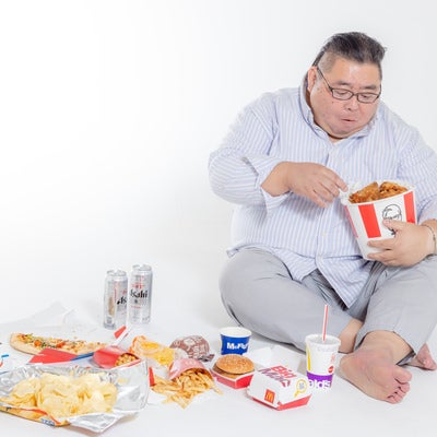 ケンタを食べながら暴飲暴食男性の写真