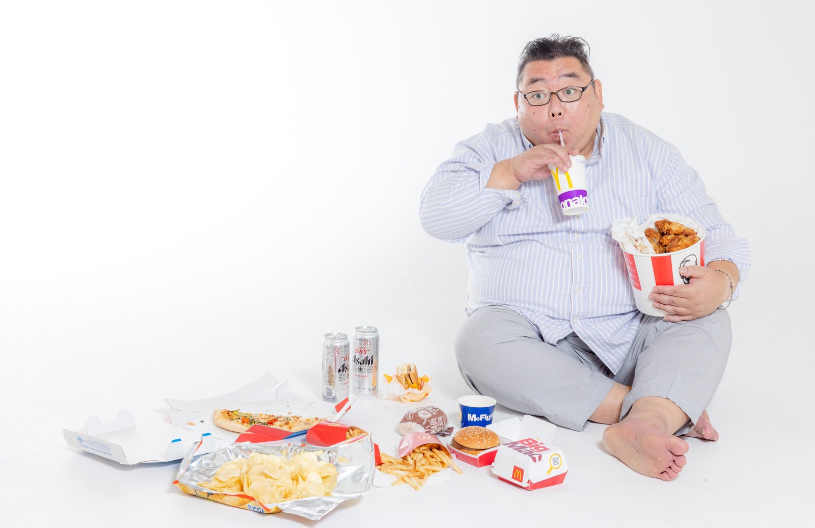 「座り込んでファーストフードを暴飲暴食するストレス男性」の写真［モデル：ダルマ親方］