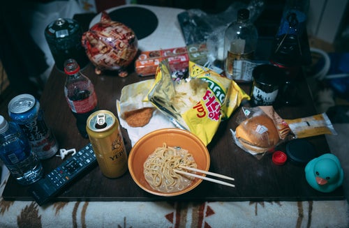 散らかった部屋で食べる孤独飯の写真