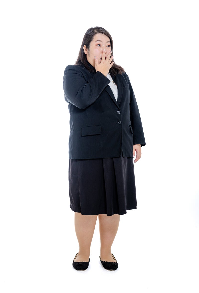 「右手で口元を隠す肥満体型の女性会社員」の写真［モデル：KANA］