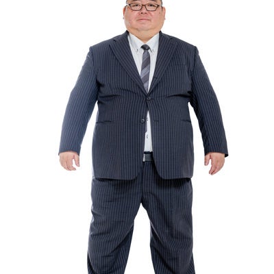 大きなサイズのスーツを切る中年男性の写真
