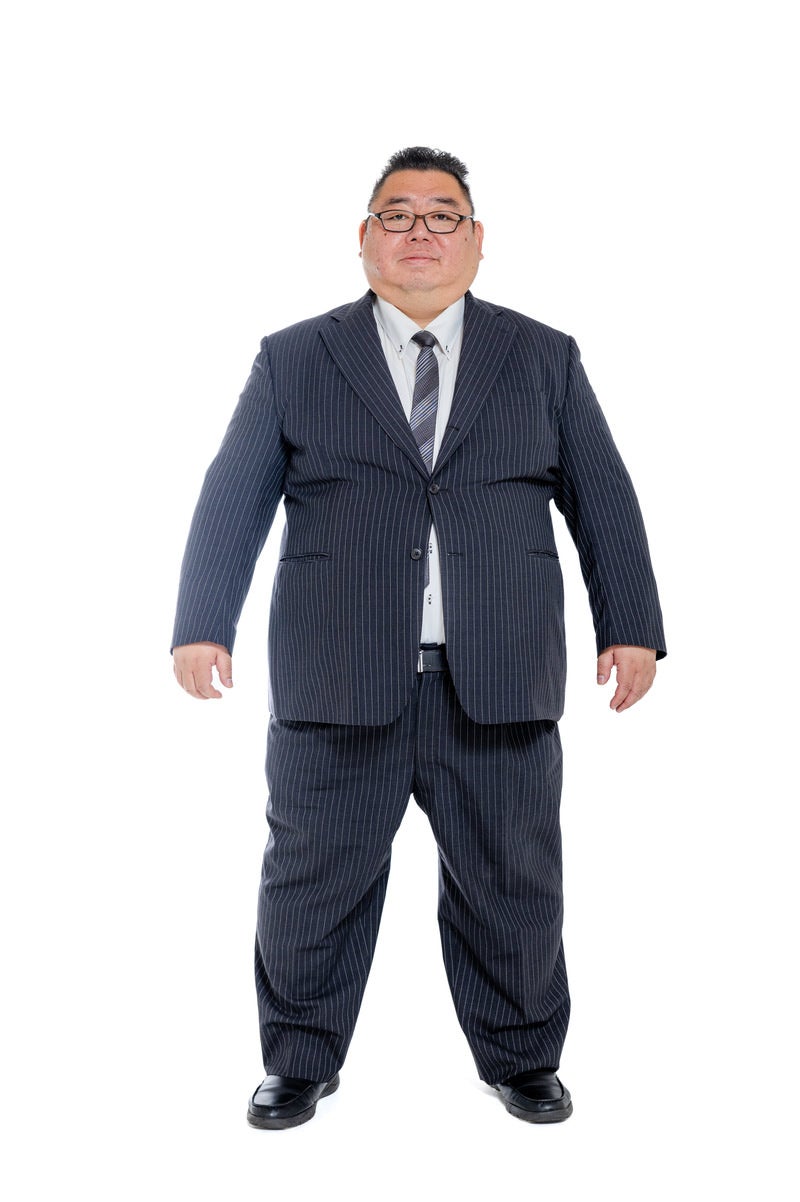 「大きなサイズのスーツを切る中年男性」の写真［モデル：ダルマ親方］