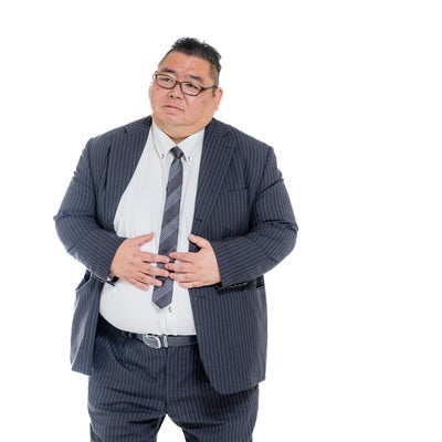 お腹を押さえる膨よかな男性の写真