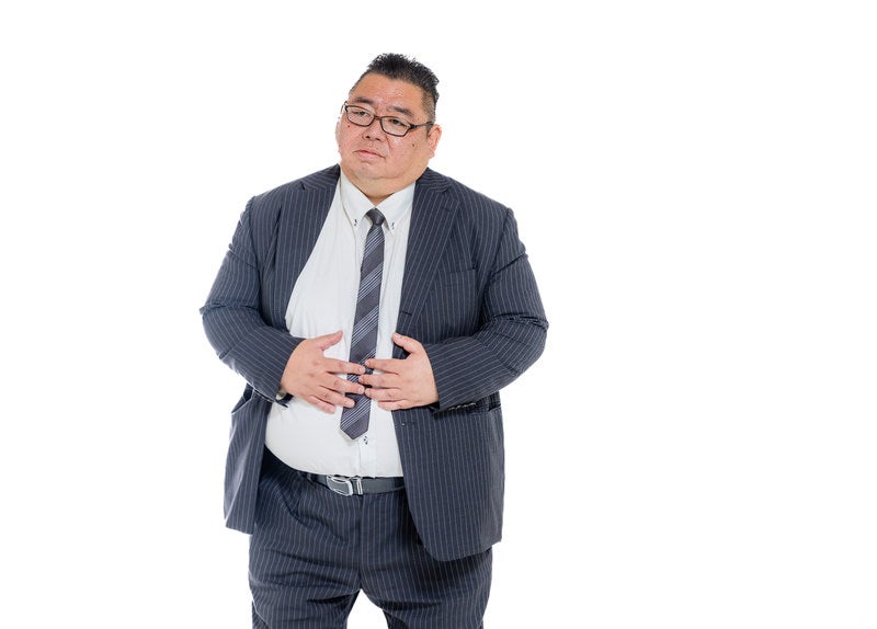 お腹を押さえる膨よかな男性の写真