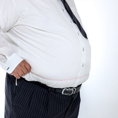 ウエストを測定する肥満体の会社員の写真