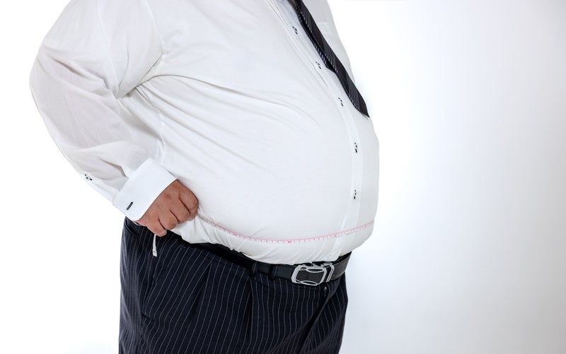 ウエストを測定する肥満体の会社員の写真