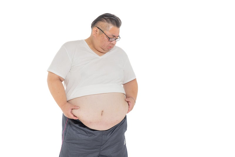 お腹に付いた贅肉をかかえる男性の写真