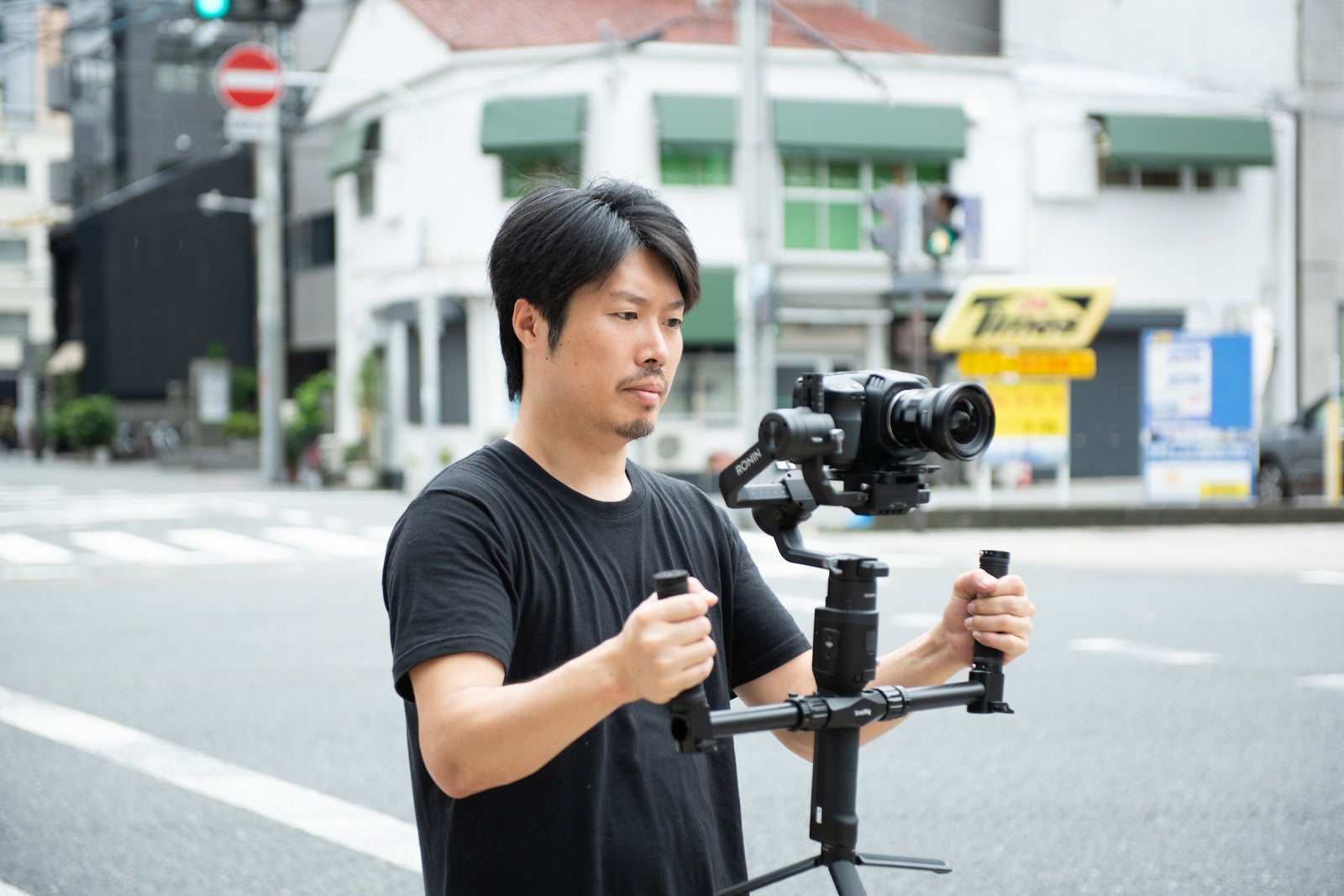 「屋外でジンバルを使った撮影をする男性カメラマン」の写真［モデル：瀧野恵太］