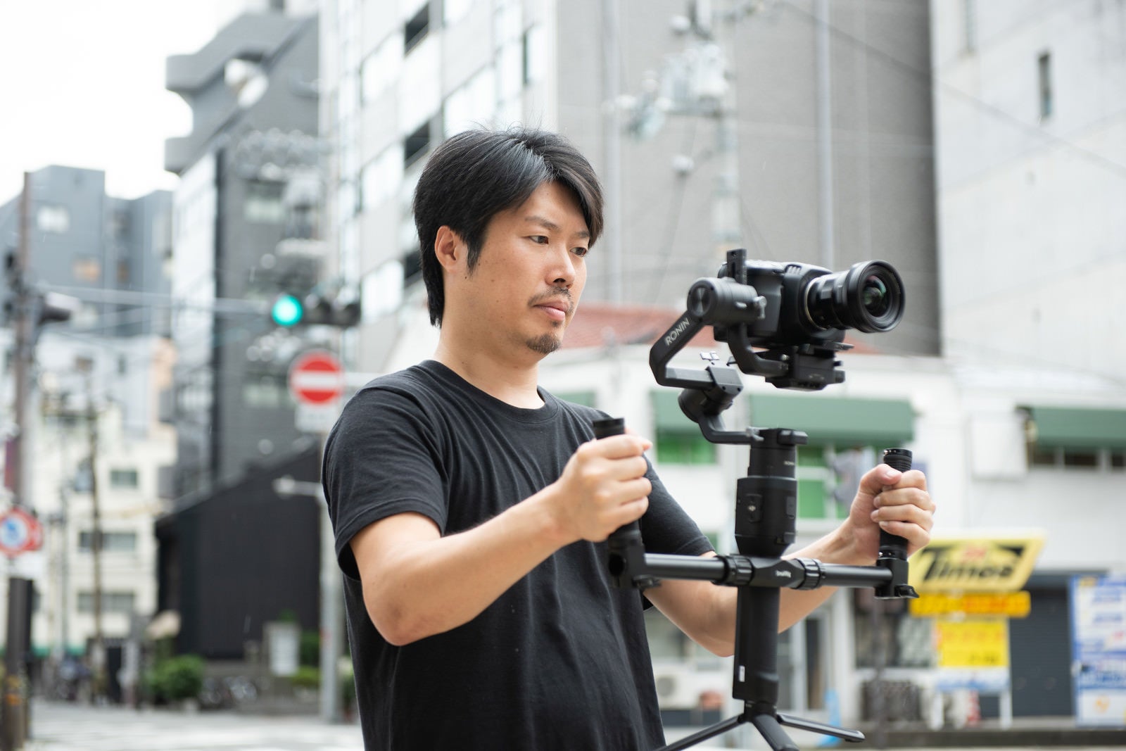 「ジンバルを使って一眼ムービー撮影をするカメラマン」の写真［モデル：瀧野恵太］