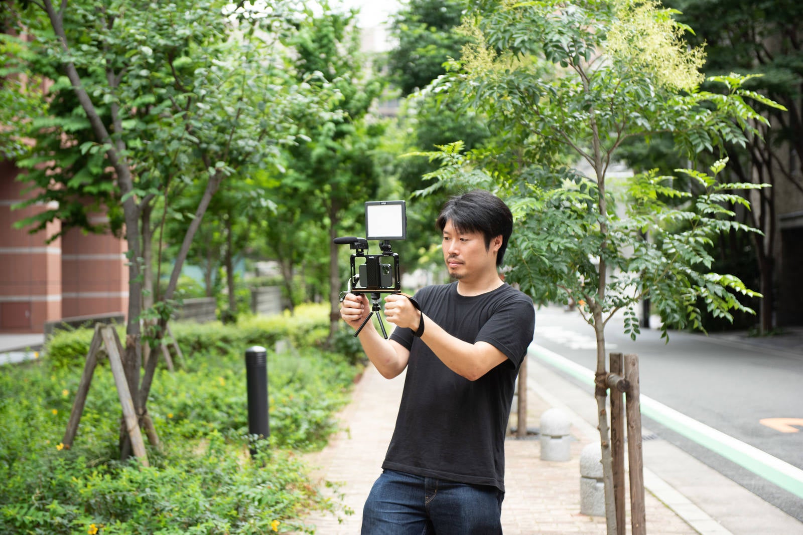 「屋外ではスマートフォンを使ってムービー撮影をする男性カメラマン」の写真［モデル：瀧野恵太］