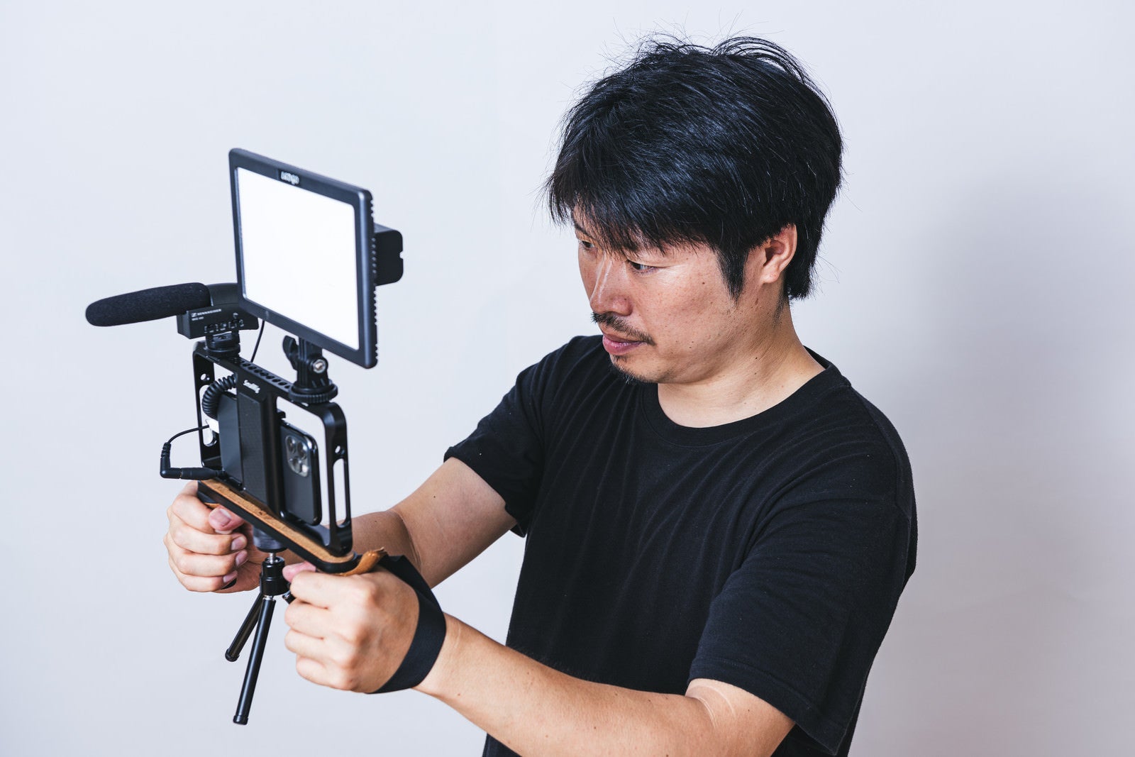「真剣な表情でスマホカメラで撮影するカメラマン」の写真［モデル：瀧野恵太］