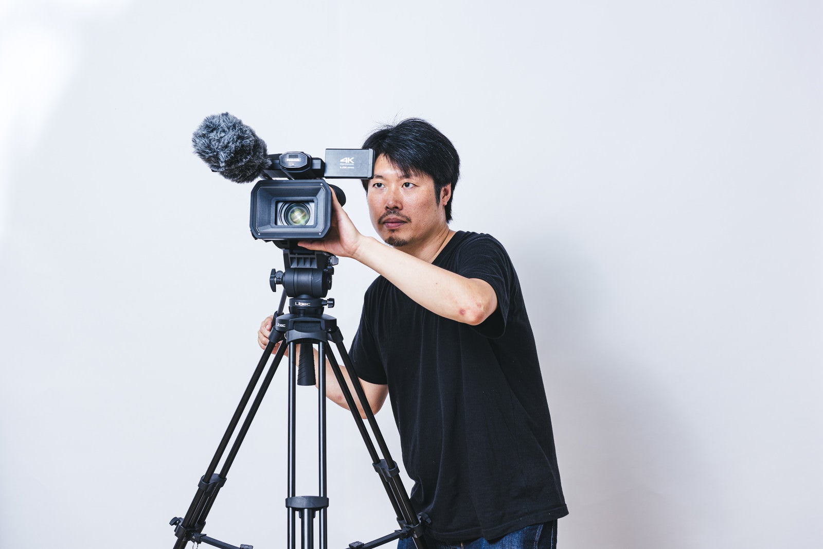 「ビデオカメラのモニターを見ながら正面上を撮影する男性」の写真［モデル：瀧野恵太］