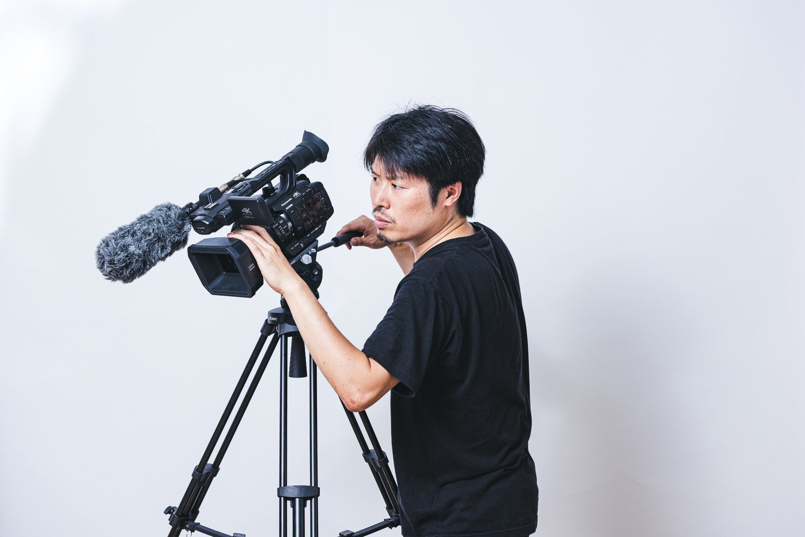 「真剣な眼差しでビデオ撮影するカメラマン」の写真［モデル：瀧野恵太］