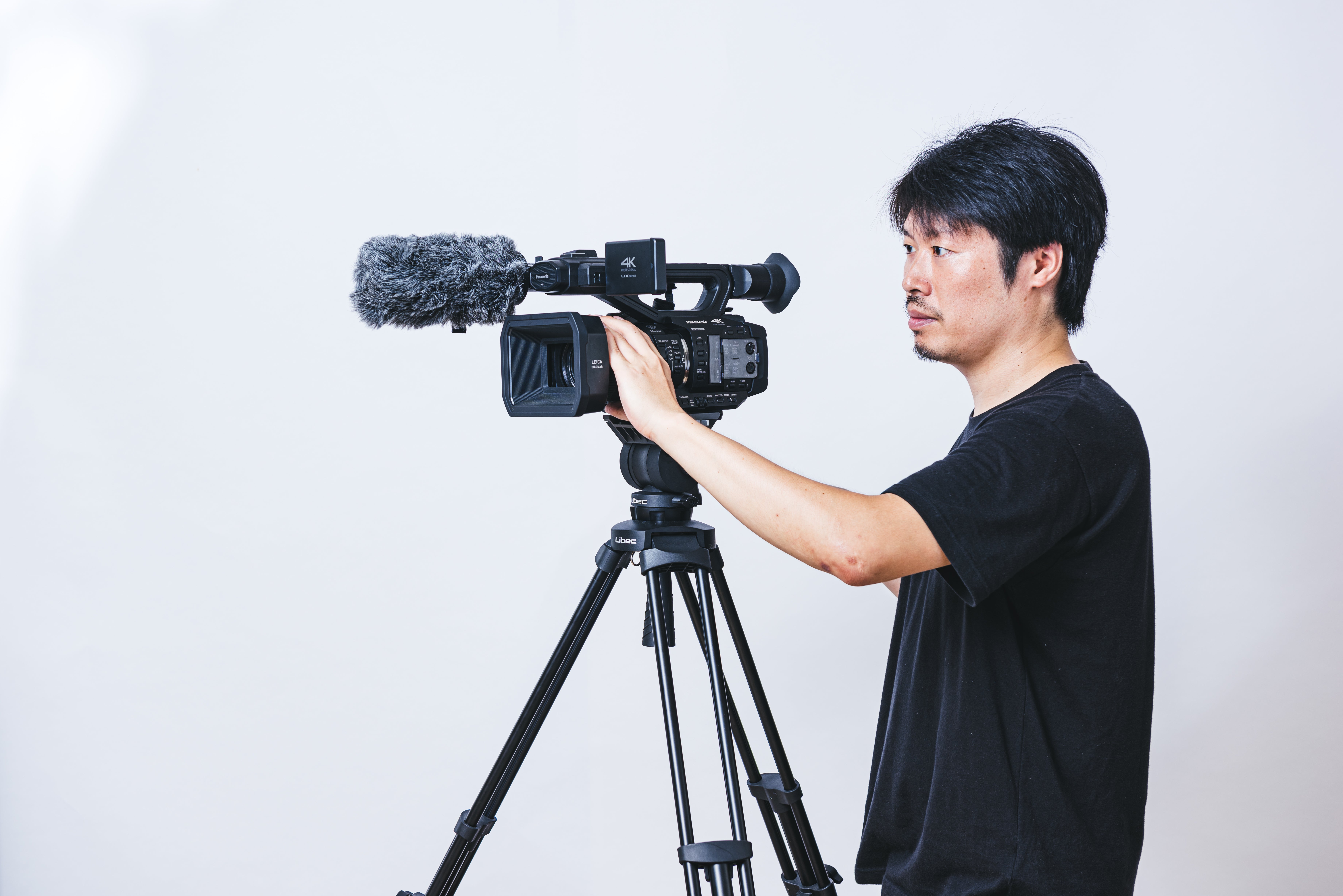 三脚にセットしたビデオカメラで撮影する男性の無料の写真素材 - ID