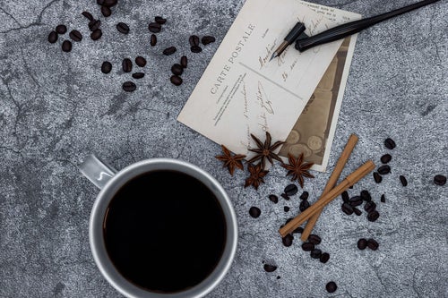 散らばるコーヒー豆と絵葉書の写真