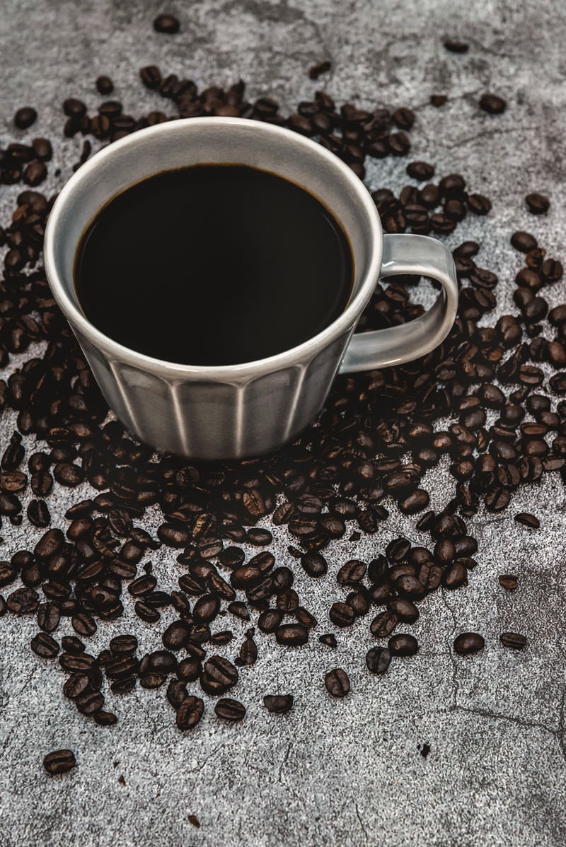 散らばるコーヒ豆と珈琲の写真