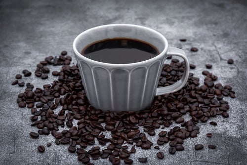 コーヒーカップ周りのコーヒー豆の写真