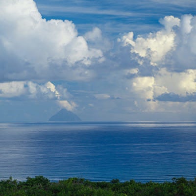 雲を映す滑らかな海に浮かぶ南硫黄島の写真