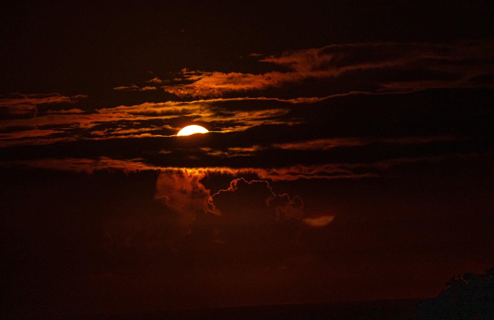 「雲を輝かせて夜空に光の帯を流す月」の写真
