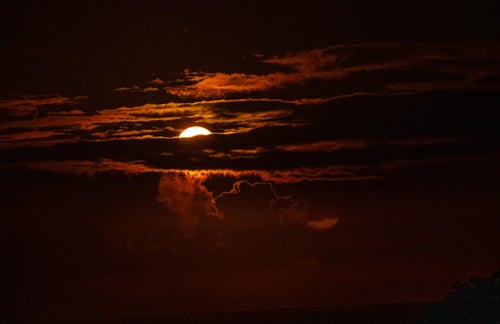 雲を輝かせて夜空に光の帯を流す月の写真