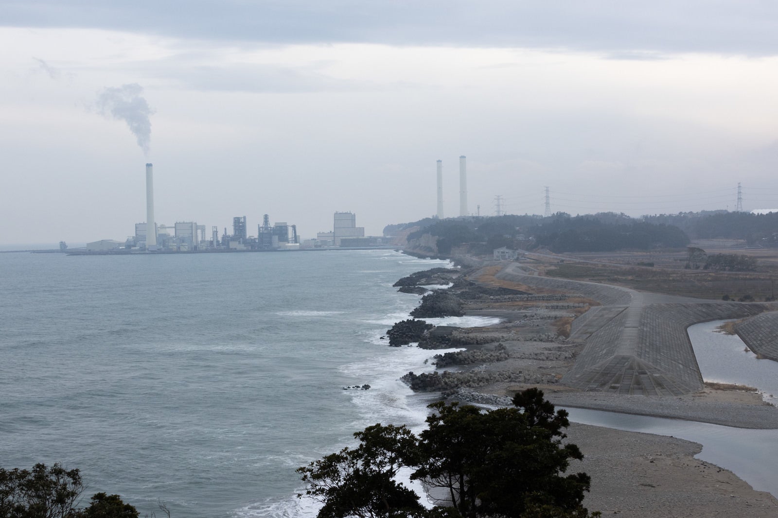 「天神岬から見える煙突のある海岸風景」の写真