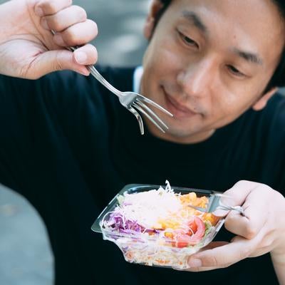 「サラダを食べる男性の写真」をAI生成したら、フォークがおかしな方向にむいて無機質な男性が生成されてしまった風の写真
