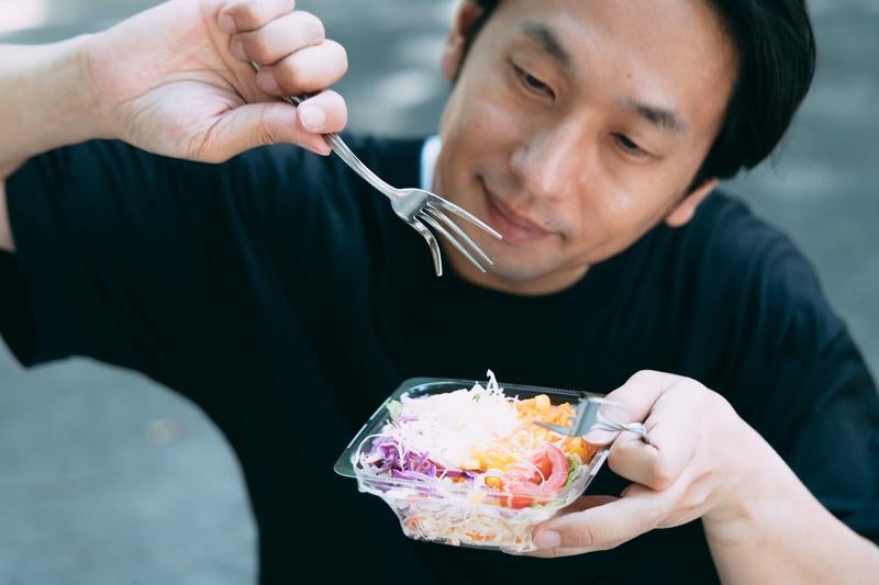 「サラダを食べる男性の写真」をAI生成したら、フォークがおかしな方向にむいて無機質な男性が生成されてしまった風の写真