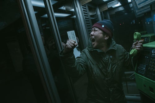 公衆電話ボックスの中で怒鳴り散らす男性の写真