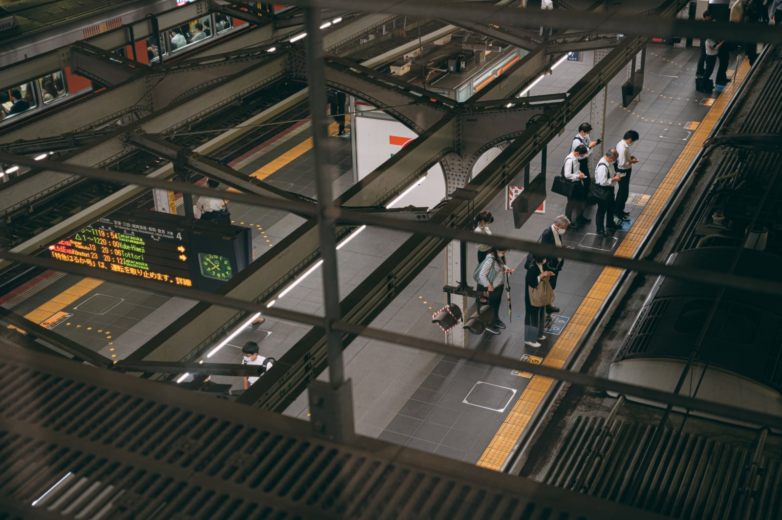 「駅のホーム上で並ぶ人たち」の写真