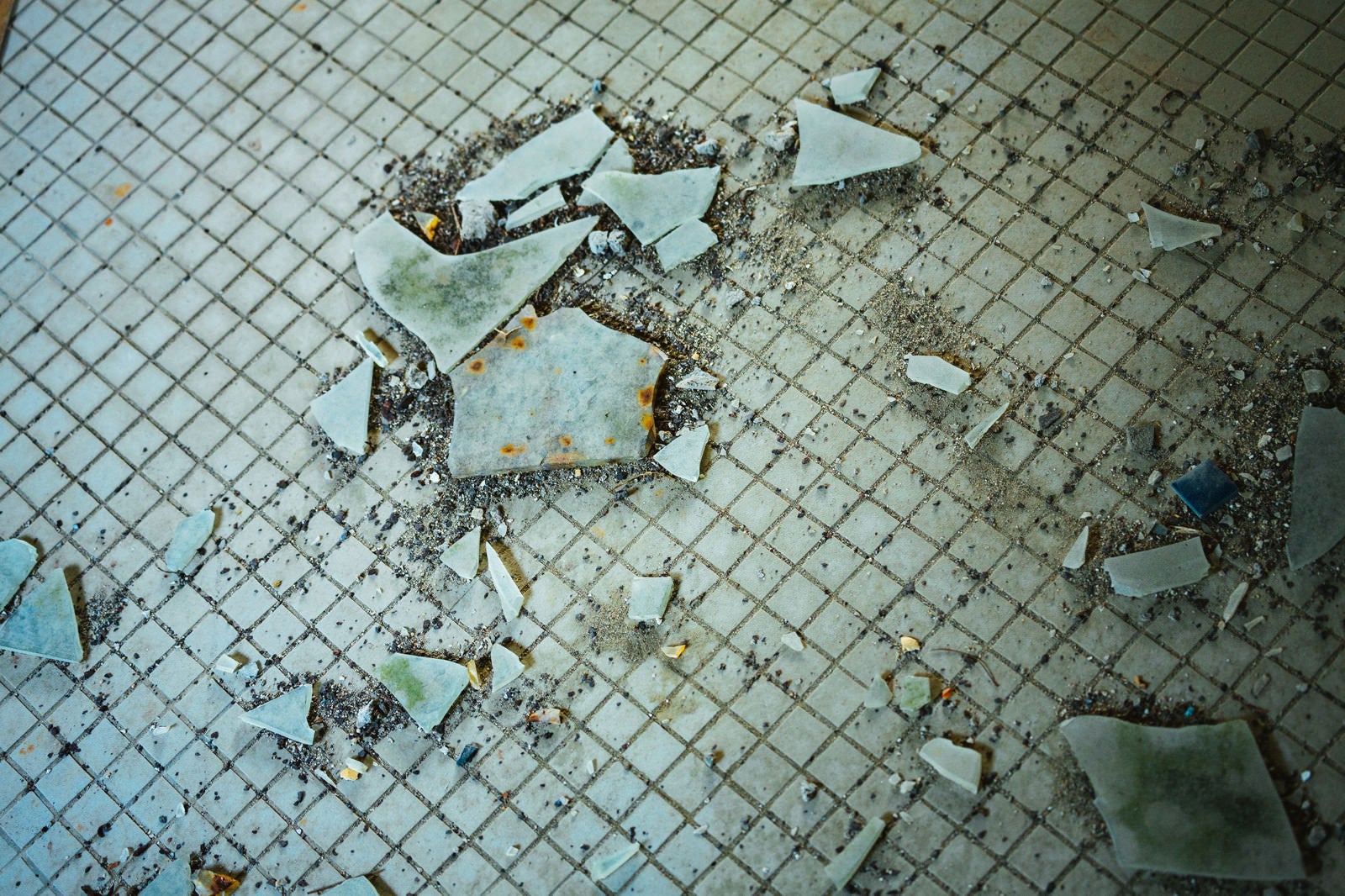 「汚れたタイルと飛び散るガラス片」の写真