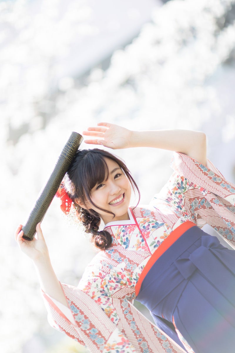 「卒業証書の丸筒を持って喜ぶ袴姿の女子大生」の写真