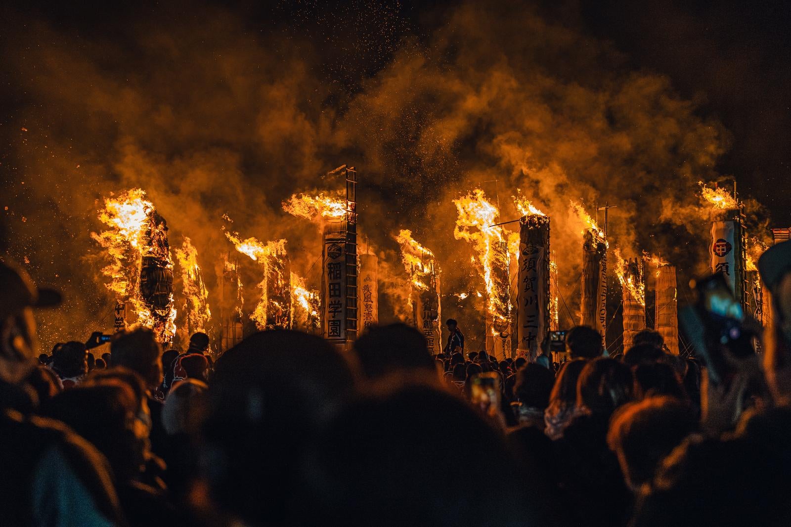 「炎に包まれる大松あかしと大勢の観客」の写真