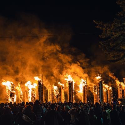 大松明から立ち上る煙を染める火祭りの炎の写真