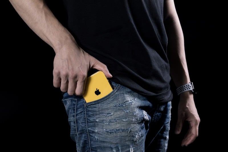 さり気無くポケットに入れる黄色のiPhoneXRの写真