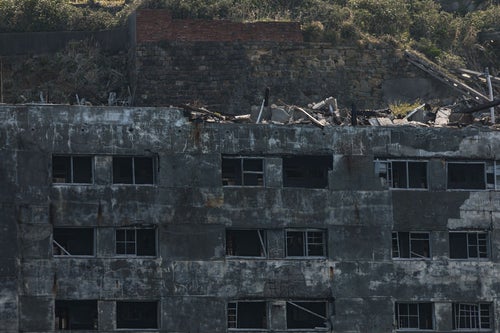 朽ちた25号棟と瓦礫（軍艦島）の写真