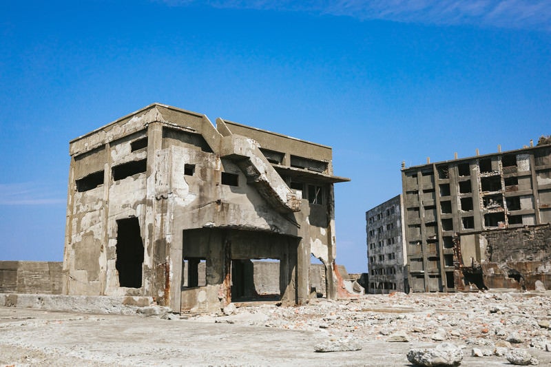 軍艦島の崩れ行く鉄筋の建物と瓦礫の写真