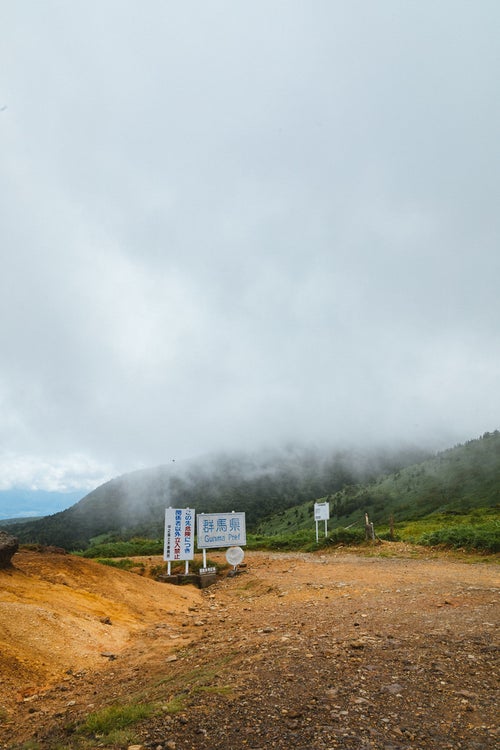 雲に覆われる毛無峠と例の看板の写真