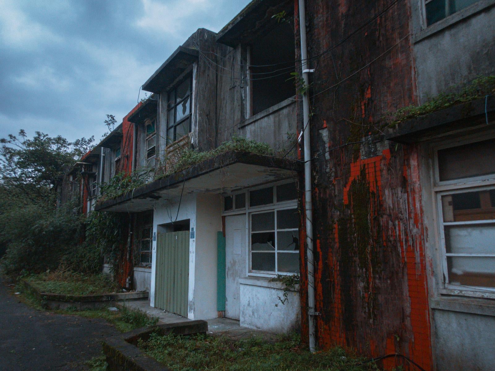 「壁が剥がれ落ちた廃アパート」の写真