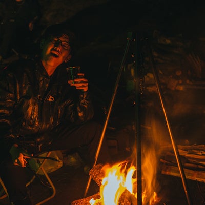 深夜のキャンプ上で飲んだくれる男性の写真
