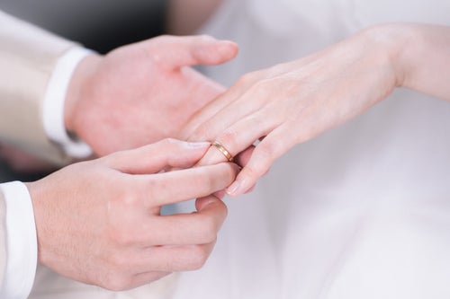 結婚指輪を左手薬指にはめる様子の写真