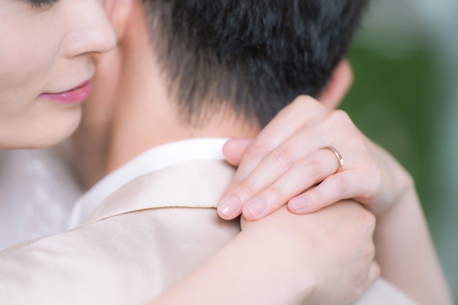 「彼を抱きしめながら結婚指輪を見つめる」の写真［モデル：たけべともこ］