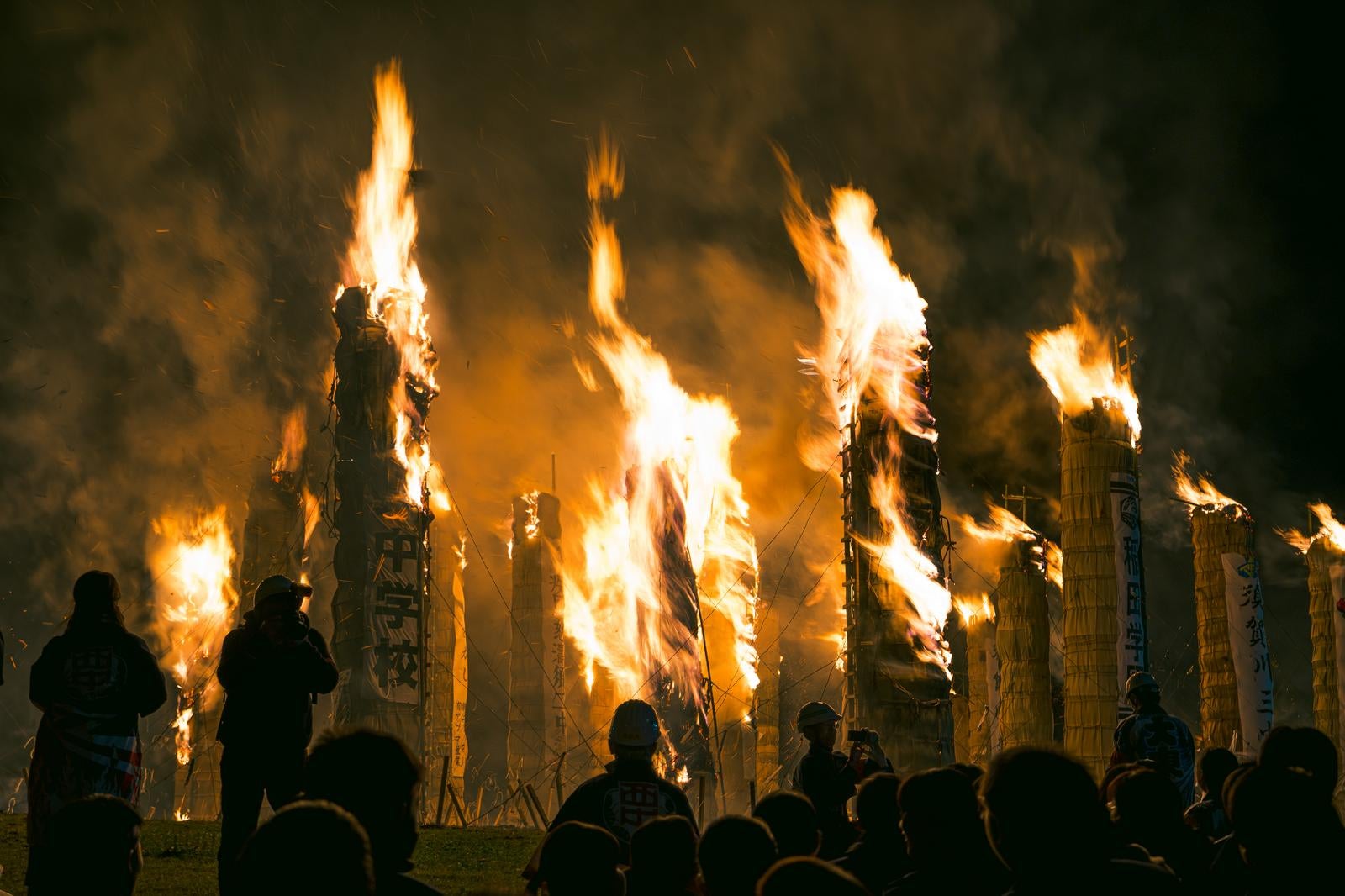 「観客の前で燃え上がる巨大な松明の火柱」の写真