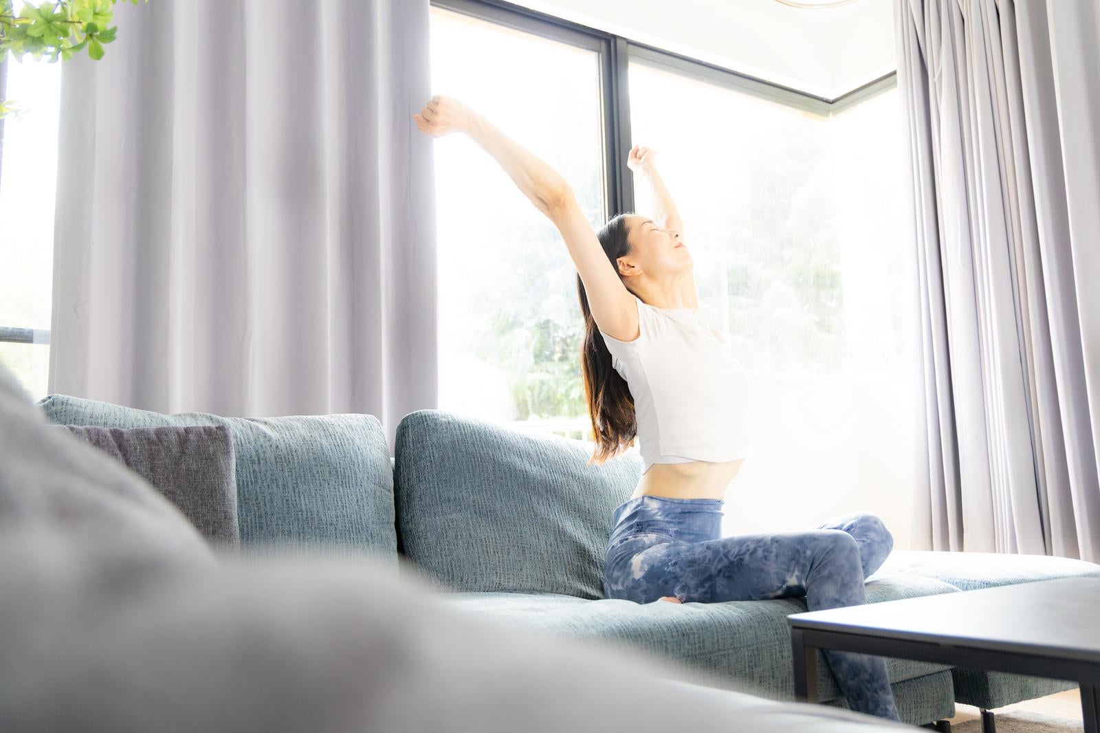 「ソファで伸びをする女性」の写真［モデル：ひるかわえみこ］